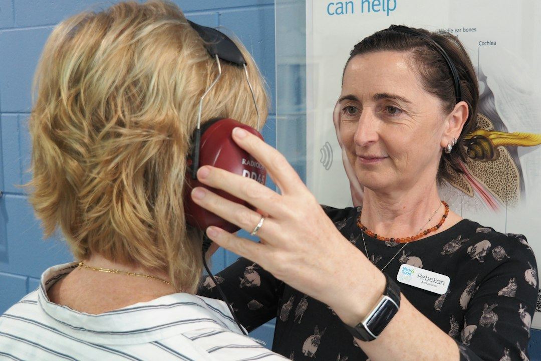 An audiologist helps a woman with a hearing test